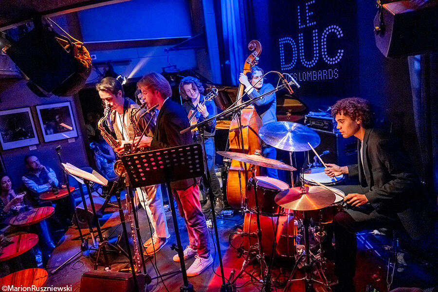 NYU Paris Jazz Ensemble at Le Duc Des Lombards (left to right: Cole Palensky, Sophia Rogers (hidden), Maya Harrison, Grant Tucker, Noah Hogan, Warren Louie, Anton Kot). Photo by Marion Ruszniewski